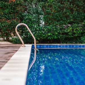 A serene swimming pool with clear blue water and a metal handrail.