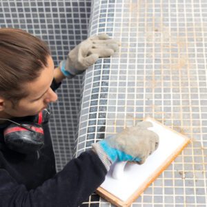 A woman installing mosaic tiles on a surface.