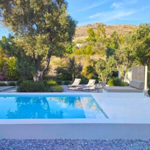 Tranquil outdoor pool area with lounge chairs and natural hillside backdrop.