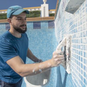 Man cleaning pool tiles with a sponge.