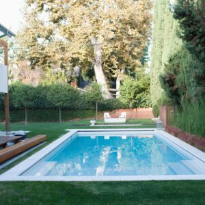 A serene backyard pool surrounded by greenery and trees.