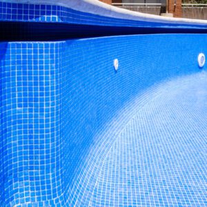 Close-up of a clean, empty blue tiled swimming pool corner.