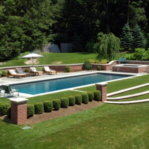 Elegant outdoor pool with lounge chairs surrounded by greenery.