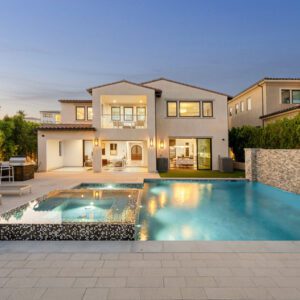 Luxurious modern house with a spacious pool at sunset.