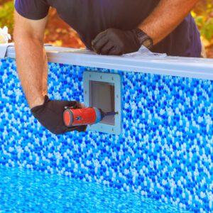 Person using a tool to clean a swimming pool wall.