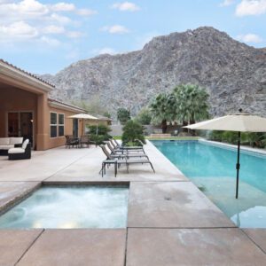 Modern outdoor pool area with mountain backdrop and seating.