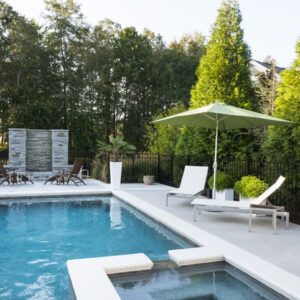 Modern backyard pool area with lounge chairs and umbrella.