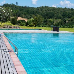 Clear blue pool water with scenic greenery in the background.