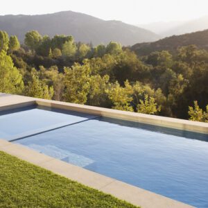A serene infinity pool overlooking lush green hills under a hazy sky.