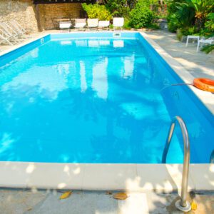 Bright outdoor swimming pool with clear blue water and lounge chairs.