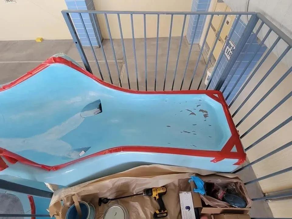 A blue plastic slide with some dirt and scratches indoors.