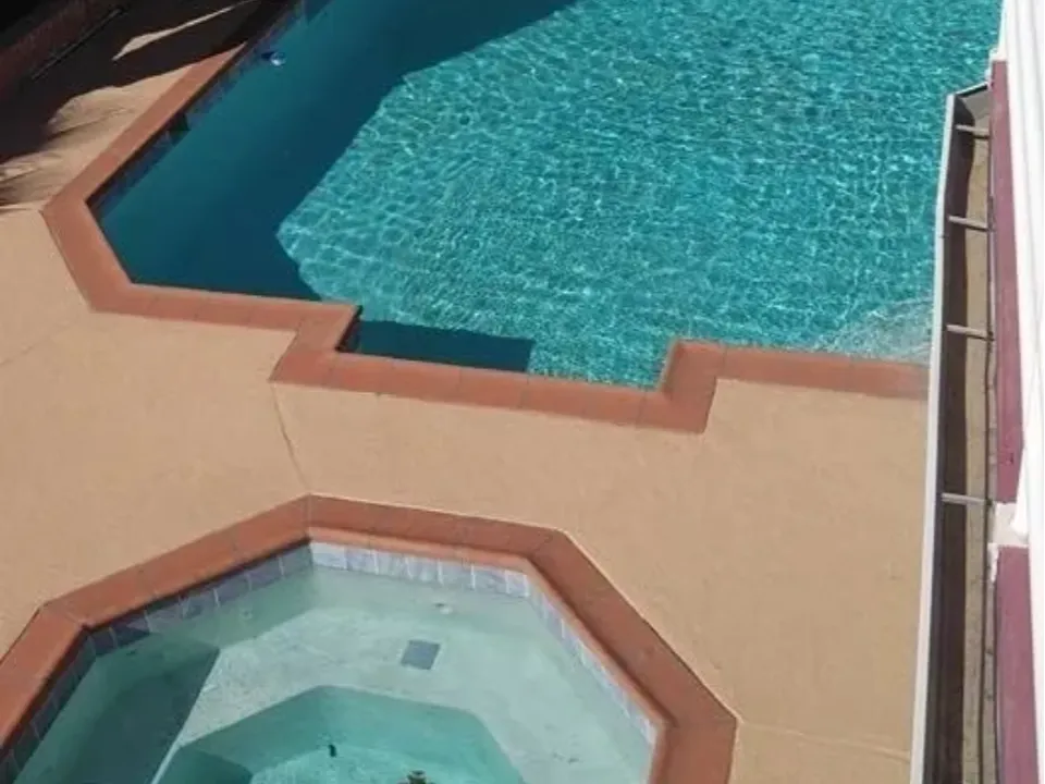 A swimming pool and a hot tub with clear blue water.