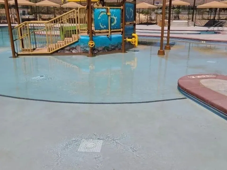Children playing in a splash pad water park with colorful structures.