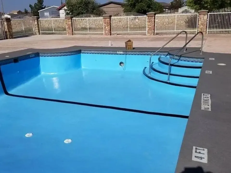 Empty blue swimming pool with steps and a hose inside.