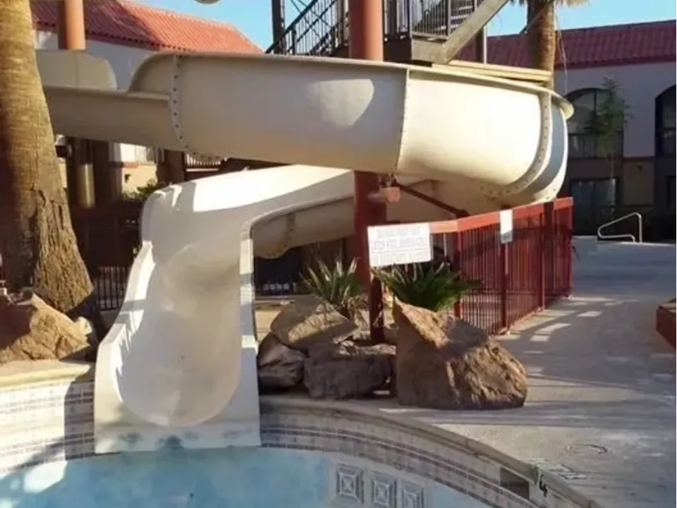 White water slide curving into a pool at a sunny outdoor area.