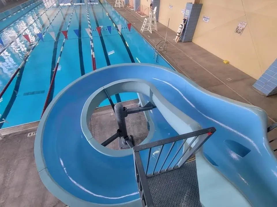 A drone flying inside an indoor swimming pool area.
