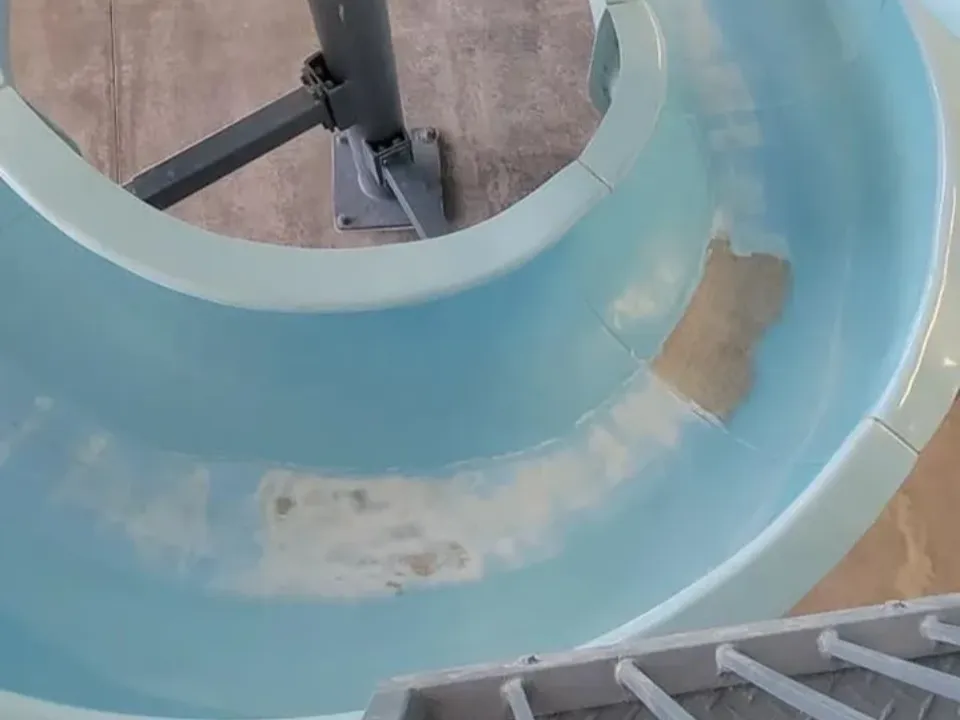 A close-up of a worn water slide with visible patches and discoloration.